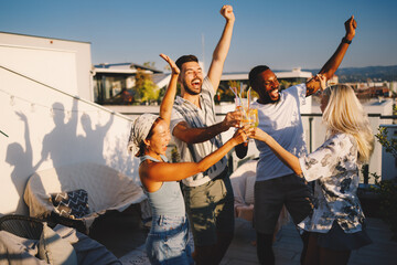 Fototapeta premium Friends celebrating rooftop party, making a toast outdoors