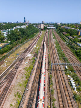 Aerial view of Ealing train station with underground trains on tracks, surrounded by urban greenery and buildings in London Borough of Ealing, England, United Kingdom.