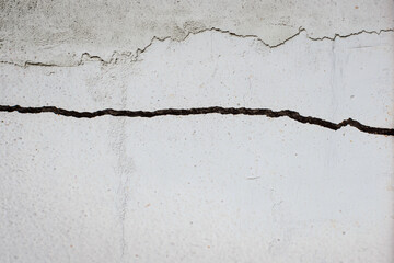 Fototapeta premium Damaged cracked concrete wall with patched old cracks.