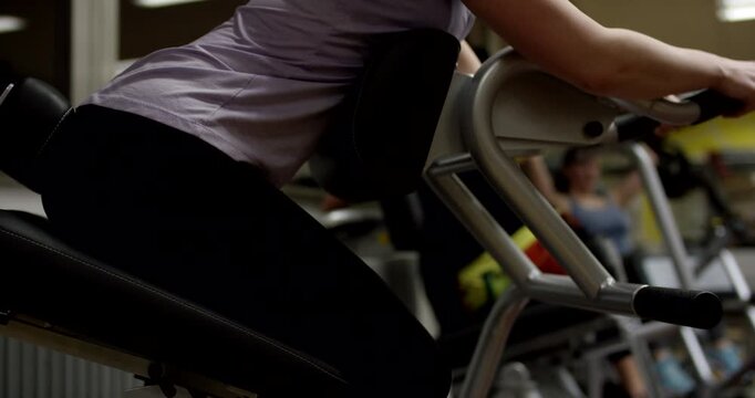 Side view of a woman performing exercises on a professional lower back extension machine in a fitness club