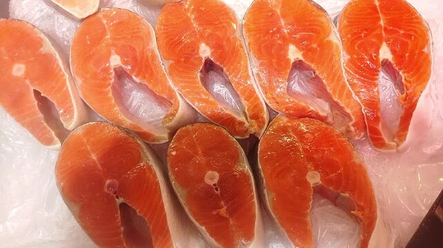 Fresh raw salmon steaks arranged in neat rows on display in close up. Bright orange fish slices prepared for cooking. Seafood, food, market, nutrition.