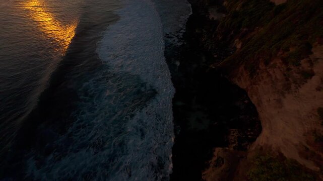 Fast FPV Drone Dive Above Karang Boma Cliff During Golden Sunset, First Person Flight Following Ocean Surf Along Dramatic Coastal Cliffs, Adventure And Exploration