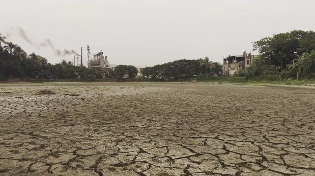 Cinematic 4K drone footage flying low over a severely cracked dry lake bed in Bangladesh. The aerial view highlights drought, water scarcity, climate change, and environmental degradation. 