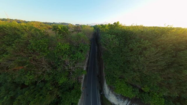 Smooth Cinematic Aerial Flight Above Winding Road Between Towering Cliffs At Pantai Tanah Barak, Wide Angle Sunrise View Of Coastal Landscape And Tropical Forest, Freedom And Exploration