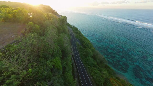 Smooth Cinematic Aerial Flight Along Coastal Road At Pantai Tanah Barak, Wide Angle Sunrise View Of Turquoise Ocean And Forested Cliffs In Golden Light, Travel And Freedom