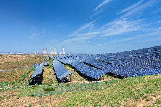 Rows of Photovoltaic Solar Panels in Arid Landscape with Thermal Power Plant in Background