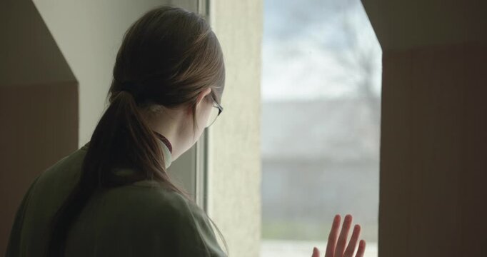 Thoughtful Girl Talks on Phone Looking out of Window. 4K 10-bit
