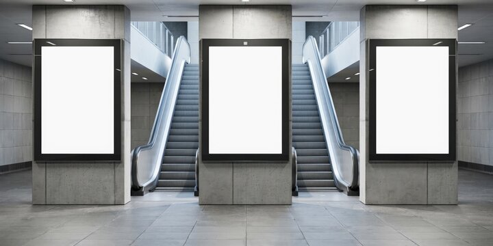 Three blank vertical advertising billboards in a subway station with escalators