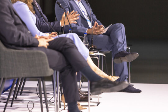 Business panel discussion with gesturing speaker and microphones at corporate conference, leadership forum and executive event. Round table political meeting.