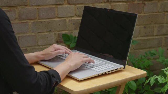 Over Elbow Back View Woman Typing on Laptop in Garden Shade