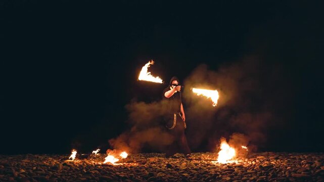 Fire performer with burning torches at night