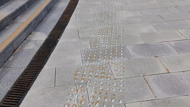 Textured pavement with tactile indicators and drainage system in urban setting
