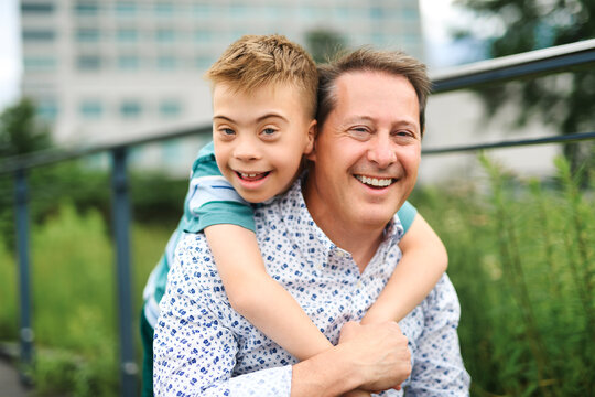 cute little child with trisomy 21 syndrome outside in summer season with his father