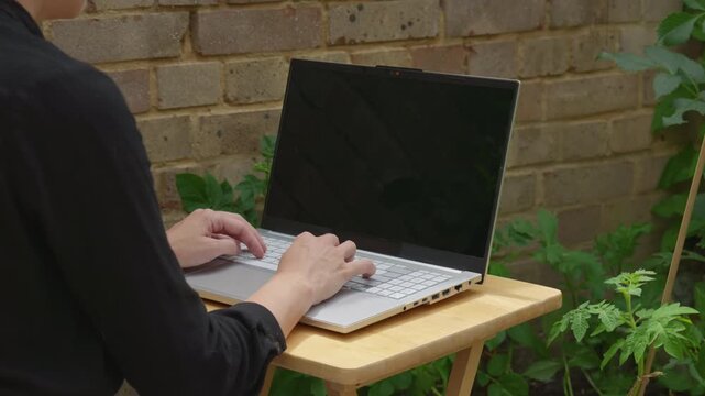 Over Shoulder Top View Woman Typing on tablet with Wireless Keyboard in Garden Shade