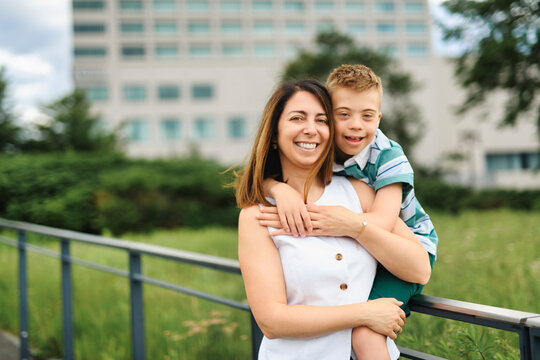 cute little child with trisomy 21 syndrome outside in summer season with his mother