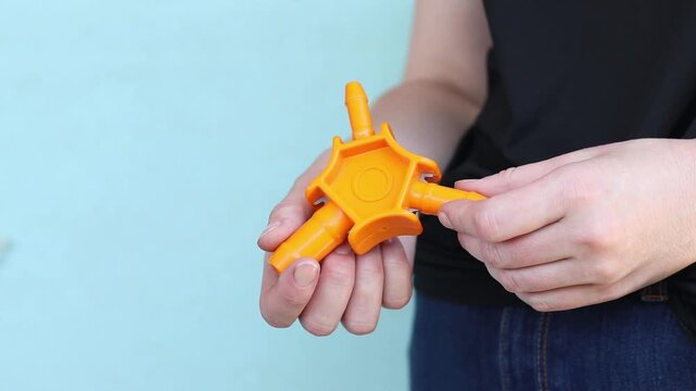 Plumbing tool for calibrating plastic pipes in a woman's hand. Manual calibrator for metal-plastic pipes (16-20-25 mm) with knives for chamfering. Orange plastic calibrator of three-beam design