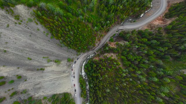 A cinematic static high-angle drone aerial shot of a winding mountain road and a river cutting through the deep rocky chasm of Red Gate in Altai.