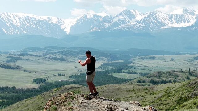 An athletic male adventurer standing with outspread arms on a mountain peak, symbolizing total freedom against a majestic snowy ridge background.