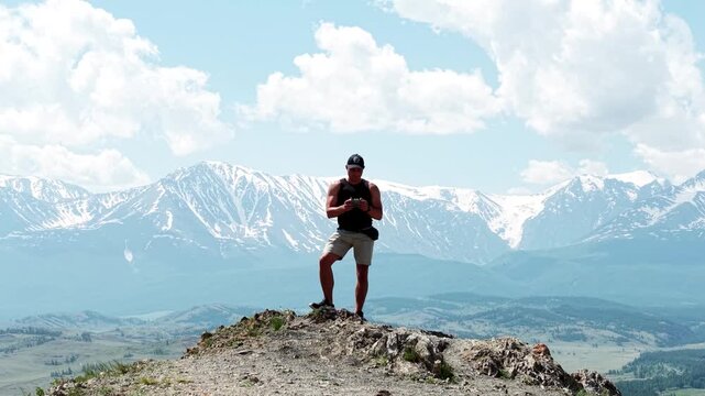 A cinematic drone revealing shot flying forward over a male adventurer to uncover a breathtaking panorama of snow-capped Altai mountain ranges.