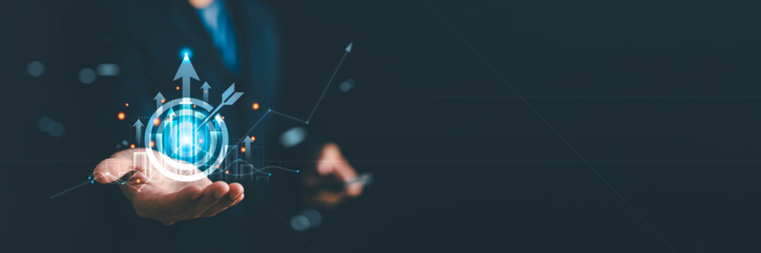 Businessman holding a glowing target board with growth charts and arrows. Concept of business strategy, financial success, goal achievement and corporate growth marketing