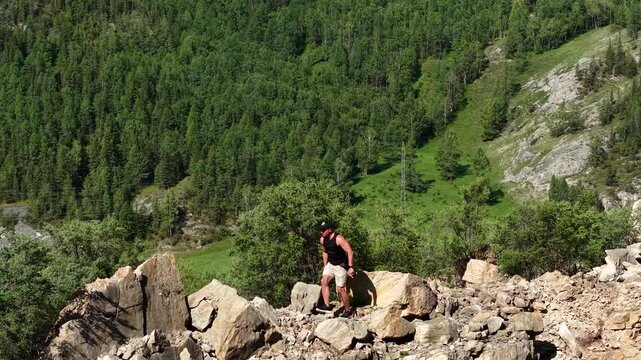 Low angle drone tracking shot of an athletic man climbing a steep mountain ridge near Maly Yaloman in Altai.