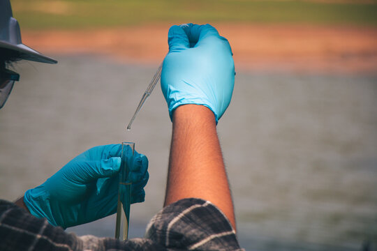 Close-up environmental specialists collecting river water samples for pollution detection.
