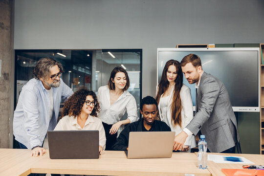 Diverse group of business team collaborating using laptops in modern office