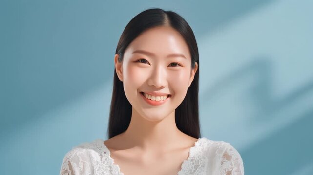 若い女性が淡い青の背景で優しく微笑み唇に指を添える白いレース服の清潔感ある美容ポートレート