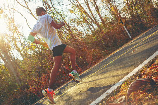 Silhouette of young man running sprinting on road. Fit runner fitness runner during outdoor workout with sunset background