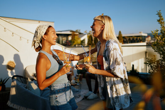 Happy young women enjoying drinks at rooftop party