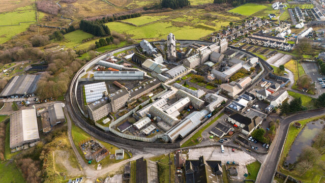 Aerial view of HM Prison Dartmoor, a historic stone prison complex surrounded by a circular wall, set within the rural landscape of Dartmoor National Park, Princetown, Devon, United Kingdom.