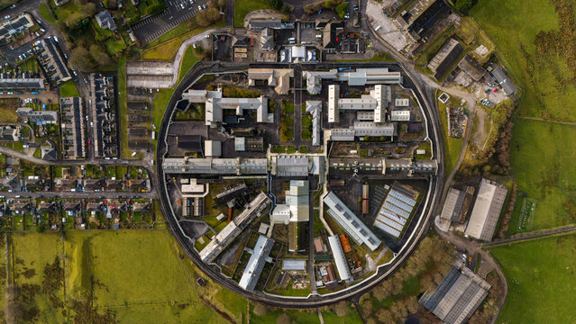 Aerial view of HM Prison Dartmoor, a historic circular prison complex surrounded by green fields and rural landscape in Princetown, Devon, United Kingdom.