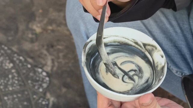 Close-up of a customer eating traditional black sesame and peanut sweet soup at a street food stall