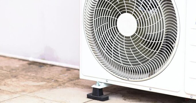 Outdoor air conditioner condenser unit with cooling fan operating. Ideal for HVAC, cooling system, energy efficiency, maintenance, residential and commercial technology, close-up