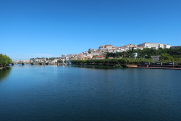 Obraz premium A panoramic view of the city of Coimbra, highlighting the Mondego River and the historic area on the hill.