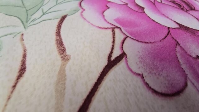 Macro close-up footage of an elegant floral print fabric, featuring detailed illustrations of vibrant pink peonies and soft yellow flowers on a textured cream background, perfect for textile and inter
