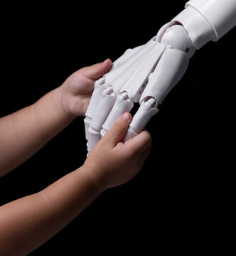 Child's hand touching a futuristic robot hand on a black background