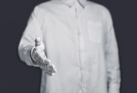 Robot hand reaching out for handshake isolated on dark gray background.