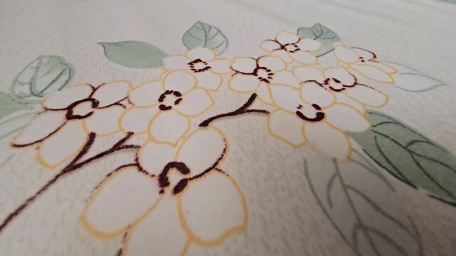Close-up of a delicate white flower pattern with soft green leaves printed on a textured fabric surface, ideal for textile design, interior decoration, and artistic wallpaper backgrounds, elegant bota