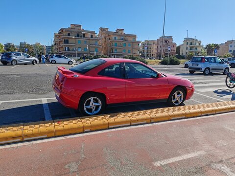 Ostia, Rome, Italy - June 29, 2026, a red Fiat Coup&eacute;, a coup&eacute;-type passenger car produced from 1994 to 2002 by the Italian automobile manufacturer FIAT, on the Ostia seafront.