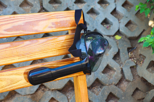 Abandoned snorkeling mask hanging on a bench, a forgotten treasure left behind by its owner, capturing the essence of summer adventures and ocean exploration.