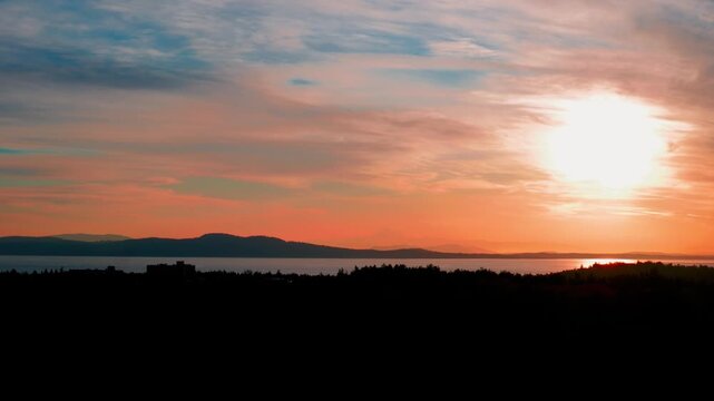 Vibrant orange sunrise over ocean bay with mountain silhouette copy space