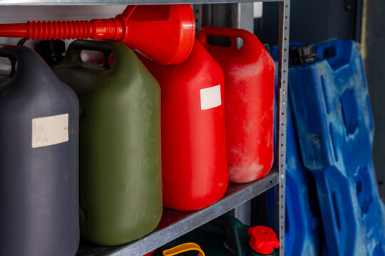 Fuel containers with pouring funnel stored on garage shelves, organized fuel storage. Concept: fuel storage system