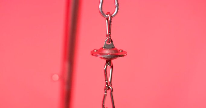 Close up of a small metal swivel hook used for hanging a barbecue grill on a red background