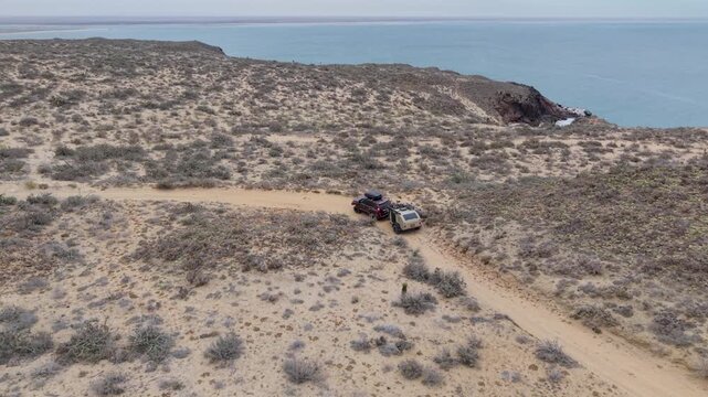 Suv pulls teardrop camper on sandy trail during overland adventure near Guerrero Negro Baja California Mexico.