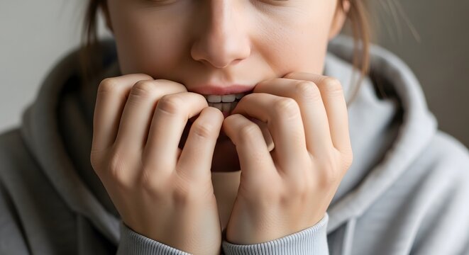 Anxious young woman biting nails close up on hands and face