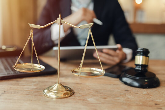 The lawyer sat in front of a laptop in a room filled with documents and smartphones, with a hammer and scales beside him, advising his female client on matters of justice and legal principles.