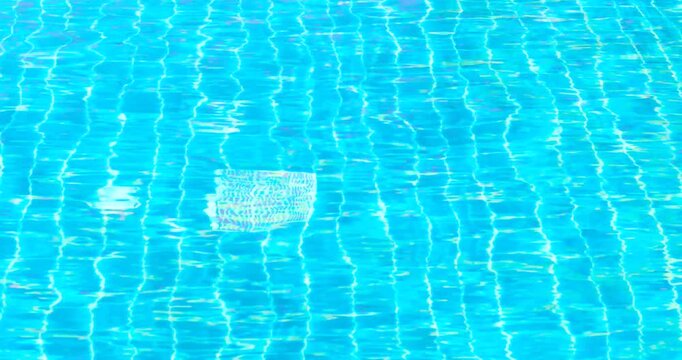 clear blue swimming pool water with shimmering reflections and tiled pattern, gentle moving ripples, abstract summer background ideal for travel, leisure, relaxation, wellness, refreshing, luxury pool