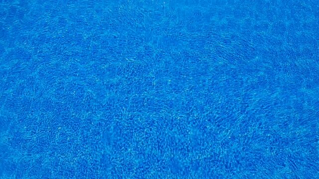 Top-down blue pool water texture with sunlight ripples for summer background
