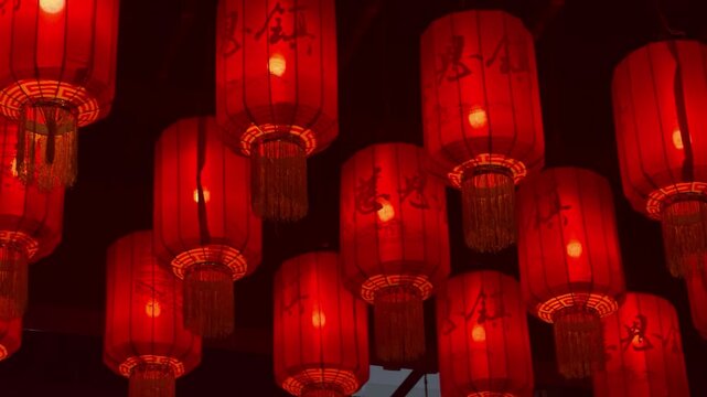 Traditional red chinese lanterns hanging in row at night. Glowing paper lamp for lunar China new year celebration. Asian culture decoration for festival atmosphere and street lighting background.